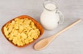 Wooden bowl with corn flakes, jug of milk and spoon Royalty Free Stock Photo