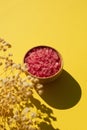 Wooden bowl filled with pink bath sea salt. Beauty treatment for spa and wellness with plant shadow. Royalty Free Stock Photo