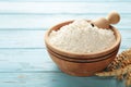 Wooden bowl with flour and flour spoon. Rice or wheat flour on blue wooden background. top view Royalty Free Stock Photo