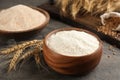 Wooden bowl of flour and wheat ears on grey table Royalty Free Stock Photo