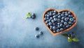 Wooden bowl with fresh blueberry on blue table top view. Organic superfood and healthy berry Royalty Free Stock Photo