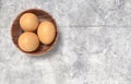 Wooden bowl ful of eggs. Placed on concrete table.