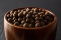Wooden bowl full of allspice jamaica pepper grains. Dried brown berries of the Pimenta dioica tree close-up. Whole pimento for Royalty Free Stock Photo