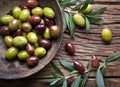 Wooden bowl full of olives and olive twigs.