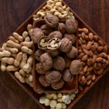 A wooden bowl full of walnuts, peanuts, almonds, cashews and macadamias on a wooden board Royalty Free Stock Photo