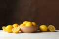 Wooden bowl and lemons against background, space for text Royalty Free Stock Photo