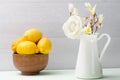 Wooden bowl with lemons and white flowers in jug. Roses in jug. Royalty Free Stock Photo