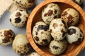 Wooden bowl and many speckled quail eggs on grey table, flat lay