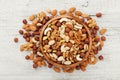 Wooden bowl with mixed nuts on white table top view. Healthy food and snack. Walnut, pistachios, almonds, hazelnuts and cashews.