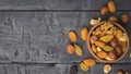 A wooden bowl with a mixture of nuts and dried fruits in a wooden bowl on a black table. Flat lay Royalty Free Stock Photo