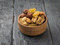 A wooden bowl with a mixture of nuts and dried fruits on a black wooden table Royalty Free Stock Photo