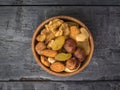 A wooden bowl with a mixture of nuts and dried fruits on a black wooden table. The view from the top Royalty Free Stock Photo