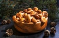 Wooden bowl with mushrooms on the background of a pine branches. Close -up on wood rustic table. Cooking delicious organic Royalty Free Stock Photo