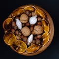 Wooden bowl with nuts, walnuts and hazelnuts. Dish decorated with Christmas baubles and slices of dried oranges