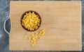 A wooden bowl of popcorn seeds on a wooden board