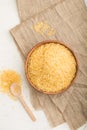 Wooden bowl with raw golden rice and wooden spoon on a white wooden background. Top view, close up Royalty Free Stock Photo