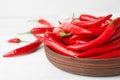 Wooden bowl with red hot chili  on white table, closeup. Space for text Royalty Free Stock Photo