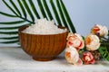 Wooden bowl with sea salt, rose and palm leaf Royalty Free Stock Photo