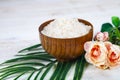 Wooden bowl with sea salt, rose and palm leaf Royalty Free Stock Photo