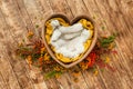 Wooden bowl in the shape of a heart with a yellow cloth and beige fur in the middle on a dark wooden background Royalty Free Stock Photo