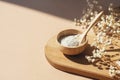 Wooden bowl with a spoon filled with white bath sea salt. Beauty treatment for spa and wellness on beige background. Royalty Free Stock Photo