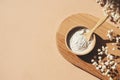 Wooden bowl with a spoon filled with white bath sea salt. Beauty treatment for spa and wellness on beige background. Royalty Free Stock Photo