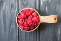 Wooden bowl with summer raspberries on black table