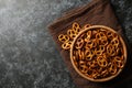 Wooden bowl with tasty cracker pretzels on napkin on black smokey background Royalty Free Stock Photo