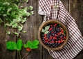 Wooden bowl with wild berries on dark wooden table.