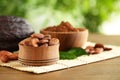 Wooden bowls of cocoa beans and powder near pod on table against blurred green Royalty Free Stock Photo