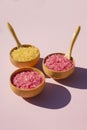 Wooden bowls with a spoon filled with pink and yellow bath sea salt. Royalty Free Stock Photo