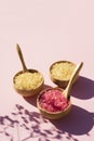 Wooden bowls with a spoon filled with pink and yellow bath sea salt. Royalty Free Stock Photo