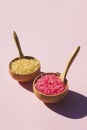 Wooden bowls with a spoons filled with pink and yellow bath sea salt. Royalty Free Stock Photo