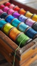 A wooden box filled with colorful spools of thread, showcasing a vibrant spectrum of textiles