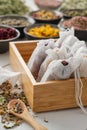 Wooden box of filter tea bags filled with dry medicinal herbs and flowers. Black bowls of medicinal plants on background. Royalty Free Stock Photo