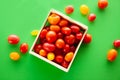 Wooden box with fresh cherry tomatoes. Red, orange and yellow cherry tomatoes on green background Royalty Free Stock Photo