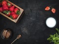 Wooden box with fresh strawberries, cup of honey, cup of milk and plate of mint leaves on vintage table. Royalty Free Stock Photo