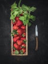 Wooden box with fresh strawberries, mint leaves and old knife on the table. Royalty Free Stock Photo