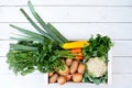 Wooden box of fresh vegetables from farmers market on white painted wood table from above. Space for text Royalty Free Stock Photo