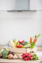 Wooden box full of fresh healthy vegetables. Broccoli carrot radish onion garlic corn on wooden kitchen table Royalty Free Stock Photo