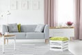 Wooden box with green pillow on striped carpet in bright scandinavian living room with grey couch and coffee table, real