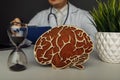 Wooden brain and hourglass in doctor& x27;s office close-up. Time and early diagnosis concept