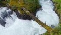 wooden bridge across Lake Lovatnet with a glacial river, view from above. moving aerial