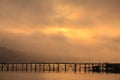 Wooden bridge across through river with foggy background at sunrise Royalty Free Stock Photo