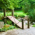 Wooden bridge across the stream in summer city garden Royalty Free Stock Photo