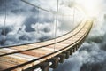 Wooden bridge in the clouds going to sunlight