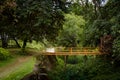 Wooden Bridge into forest with waterway in summer in side view