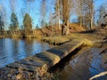 A wooden bridge goes through the lake. Walking on footbridge during midday. Lakeside and bridge landscape on a sunny day