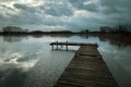 Wooden bridge on the lake, rainy clouds on the evening sky