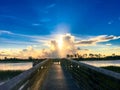 Sun setting behind clouds behind a wooden pier on a lake Royalty Free Stock Photo